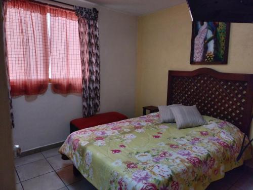 a bedroom with a bed and a red chair at HOSPEDAJE 4Casa San Francisco in Zacatlán