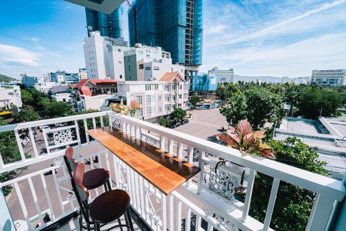 a balcony with a wooden table and chairs and a city at Blossom Sea Homestay Quy Nhơn in Quy Nhon