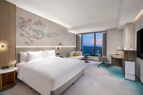 Habitación de hotel con cama blanca grande y escritorio. en Crowne Plaza Shanghai Jinxiu, an IHG Hotel en Shanghái