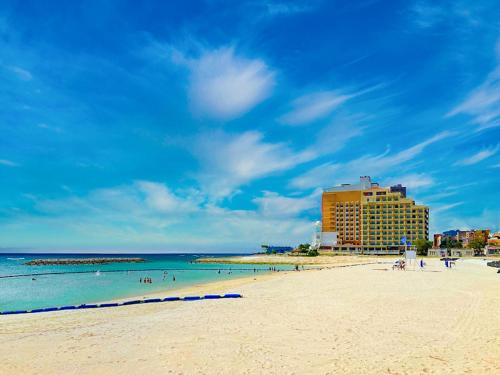 a beach with people in the water and a hotel at Vessel Hotel Campana Okinawa in Chatan