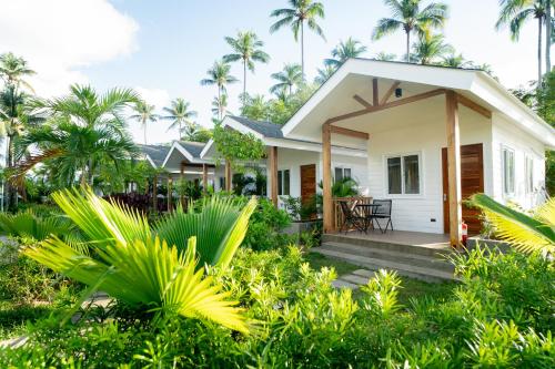 a cottage in the middle of a garden with palm trees at Nacpan Beach Villas Managed by H Hospitality Group in El Nido