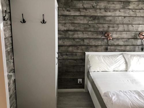 1 dormitorio con cama blanca y pared de madera en Holiday home LIMA II en Lima
