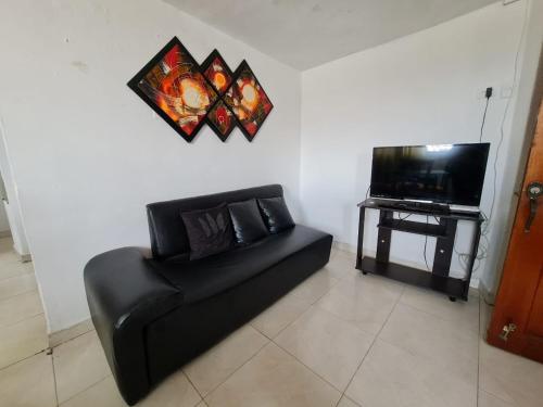 sala de estar con sofá negro y TV en EDIFICIO MENDEZ, en Cartagena de Indias
