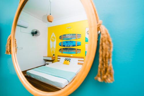 espejo que refleja un dormitorio con cama. en Blossom Sea Homestay Quy Nhơn en Quy Nhon
