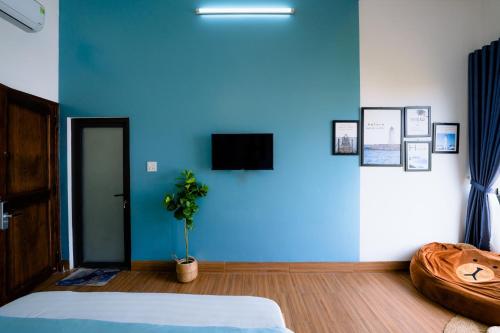 a bedroom with a blue wall with a bed and a plant at Blossom Sea Homestay Quy Nhơn in Quy Nhon