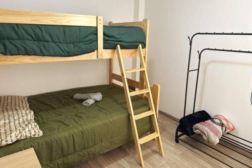a bunk bed with a ladder next to a green bed at Morada Apartamentos in Tacna