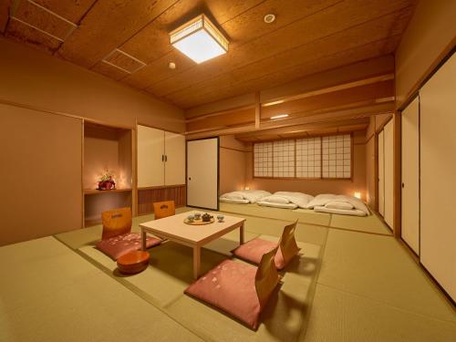 Cette chambre comprend deux lits, une table et des chaises. dans l'établissement Yukai Resort Hana-Saichoraku, à Kaga