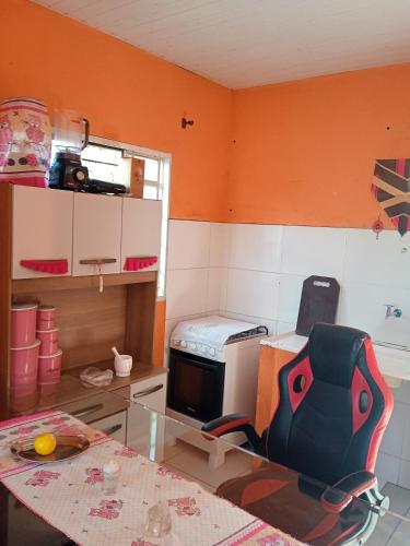 a kitchen with orange walls and a table and a microwave at Conforto in Alto Paraíso de Goiás