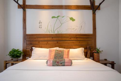 sypialnia z białym łóżkiem z drewnianym zagłówkiem w obiekcie Zhangjiajie Yueting Eco Inn w mieście Zhangjiajie