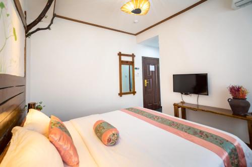 a bedroom with a bed and a flat screen tv at Zhangjiajie Yueting Eco Inn in Zhangjiajie