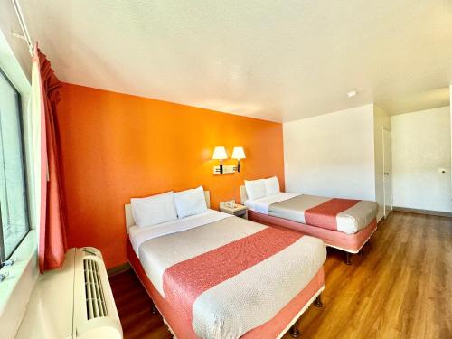 two beds in a room with orange walls and wooden floors at Motel 6-Bellflower, CA - Los Angeles in Bellflower