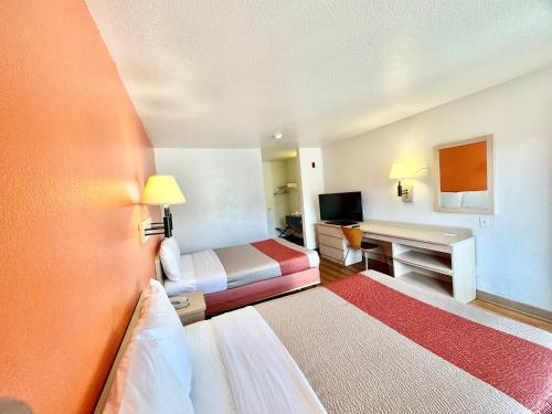 a hotel room with two beds and a desk at Motel 6-Bellflower, CA - Los Angeles in Bellflower