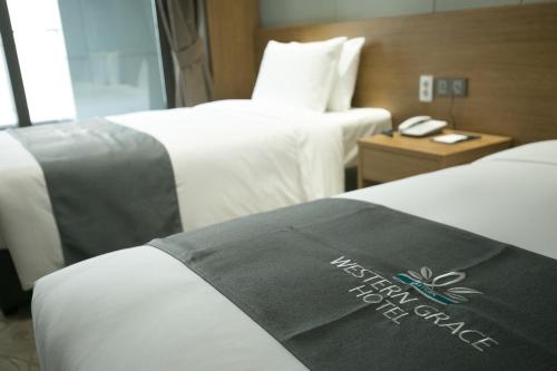 a hotel room with two beds and a phone at Western Grace Hotel Incheon in Incheon