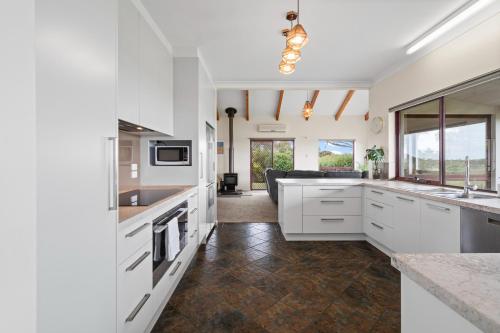 a kitchen with white cabinets and a living room at Sea Breeze - Spacious home with lovely ocean views in Port Elliot