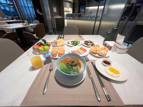 a table with a bowl of food and plates of food at The Meixi Lake, Changsha Marriott Executive Apartments in Changsha