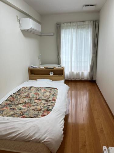 - une chambre avec un grand lit et une fenêtre dans l'établissement リバーサイドひの, à Hino