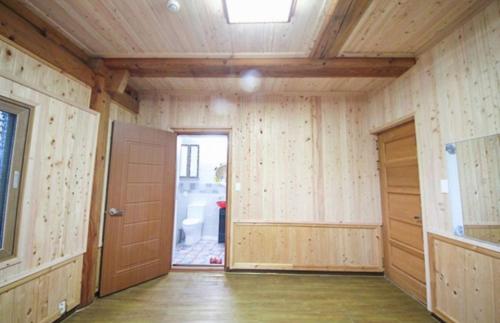 um quarto vazio com paredes de madeira e uma porta em Doyosae Hanok Pension em Suncheon