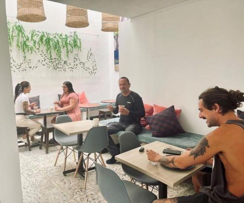 un grupo de personas sentadas en mesas en una habitación en DeRequka Hostel, en Pereira