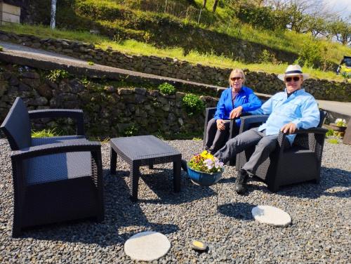 two older people sitting in chairs in a yard at Kumano Kodo Nagano Guesthouse in Tanabe