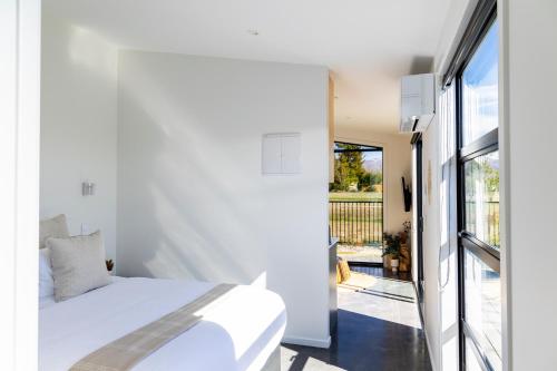 a bedroom with a white bed and a balcony at Ben Ohau Views The Studio in Twizel