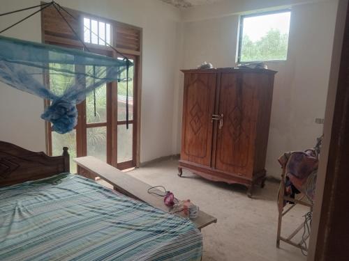 1 dormitorio con 1 cama y armario de madera en Natural first, en Matara