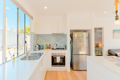 a kitchen with white cabinets and a stainless steel refrigerator at Private and peaceful house near the Beach in Coolum Beach