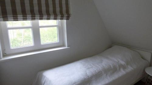 een kleine slaapkamer met een bed en een raam bij Reetdachhaushaelfte-1 in Sankt Peter-Ording