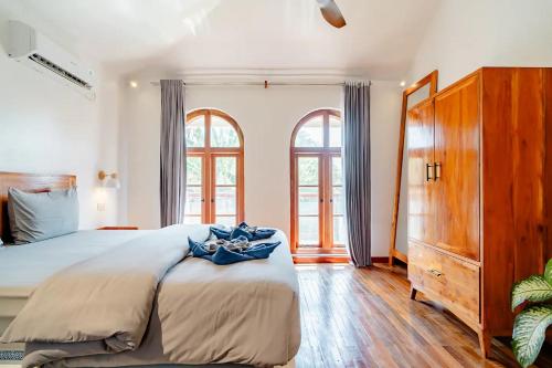 1 dormitorio con 1 cama grande y 2 ventanas en Markisa Villas - Private Pool Villas on Gili Air, en Gili Air