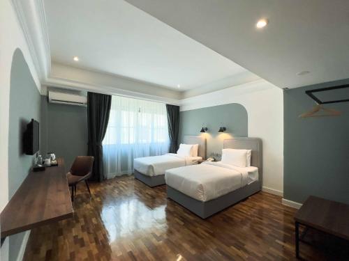 a hotel room with two beds and a television at Hotel Seri Costa in Malacca