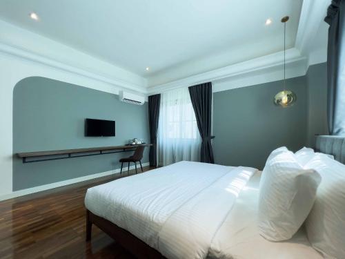 a bedroom with a white bed and a television at Hotel Seri Costa in Malacca