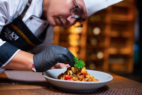 a person in black gloves preparing a plate of food at THE 1O1 Bali Fontana Seminyak in Legian