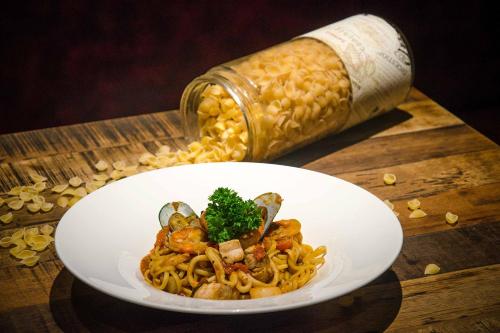 a white plate of pasta and a bottle on a table at THE 1O1 Bali Fontana Seminyak in Legian