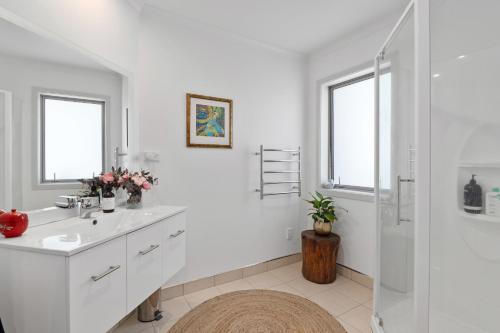 uma casa de banho branca com um lavatório e um chuveiro em Banksia Retreat - Blenheim Holiday Home em Blenheim