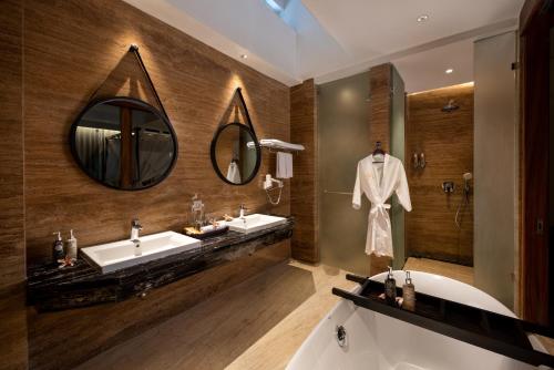 a bathroom with two sinks and a tub and a mirror at Mokko Suites Batubelig in Canggu