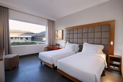 a hotel room with two beds and a large window at THE 1O1 Bali Fontana Seminyak in Legian