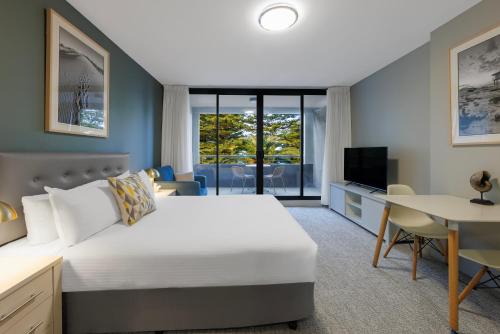 1 dormitorio con 1 cama, escritorio y TV en Quest Cronulla Beach, en Cronulla