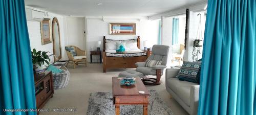 a living room with a couch and a bed at The Glade, peace among the trees on the river in Urunga