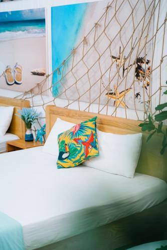 a bed with white sheets and a colorful pillow at Blossom Sea Homestay Quy Nhơn in Quy Nhon