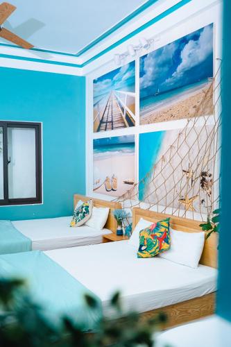 two beds in a room with a mural of a beach at Blossom Sea Homestay Quy Nhơn in Quy Nhon