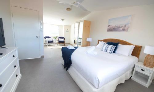 a bedroom with a white bed and a television at Nelson Bay Breeze in Nelson Bay