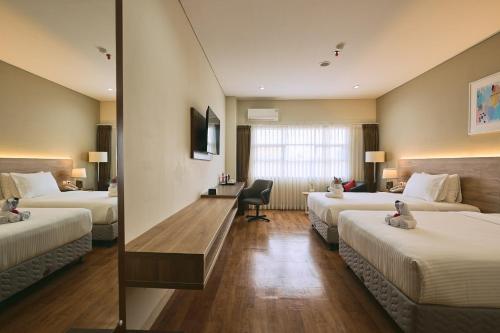 a hotel room with two beds and a desk at Horison TC UPI Serang in Banjar