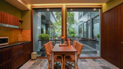 a kitchen with a table and chairs and a balcony at CHiEM HoiAn - The Beachside Boutique Hotel & Villa in Hoi An