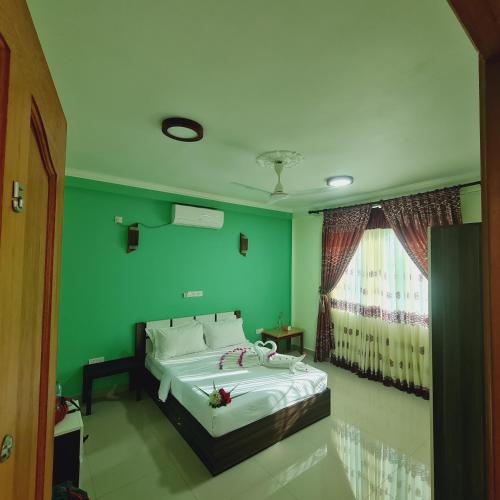 a green bedroom with a bed and a window at Aanirustayinn in Hoarafushi