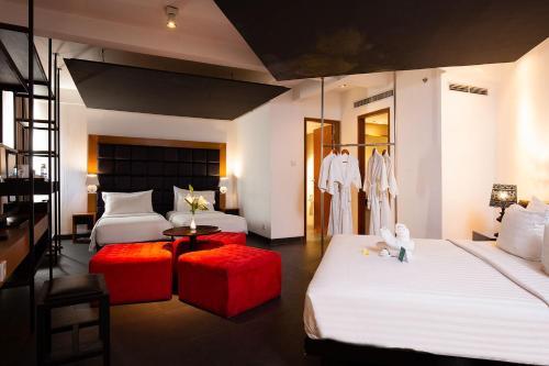 a hotel room with two beds and red ottoman at THE 1O1 Bali Fontana Seminyak in Legian