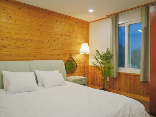 a bedroom with a white bed and a window at Seogwipo Classic in Seogwipo