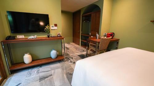 a bedroom with a bed and a flat screen tv at CHiEM HoiAn - The Beachside Boutique Hotel & Villa in Hoi An