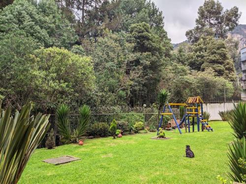 a yard with a playground and a cat sitting in the grass at Awesome view and functional in the mountain ! in Bogotá