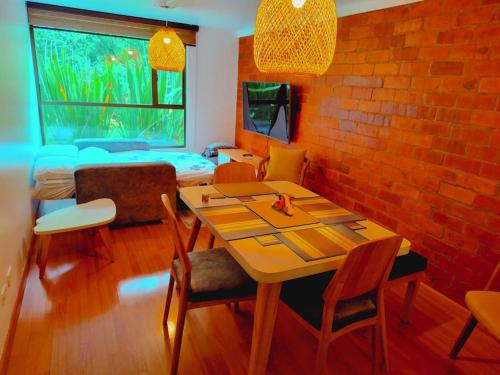 a dining room with a table and chairs and a brick wall at Awesome view and functional in the mountain ! in Bogotá