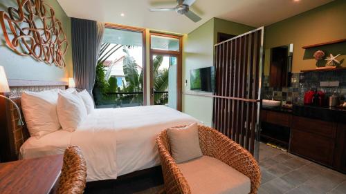 a bedroom with a bed and a table with a chair at CHiEM HoiAn - The Beachside Boutique Hotel & Villa in Hoi An