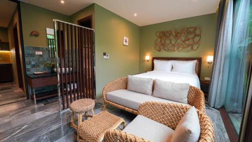 a bedroom with a bed and a chair and a couch at CHiEM HoiAn - The Beachside Boutique Hotel & Villa in Hoi An